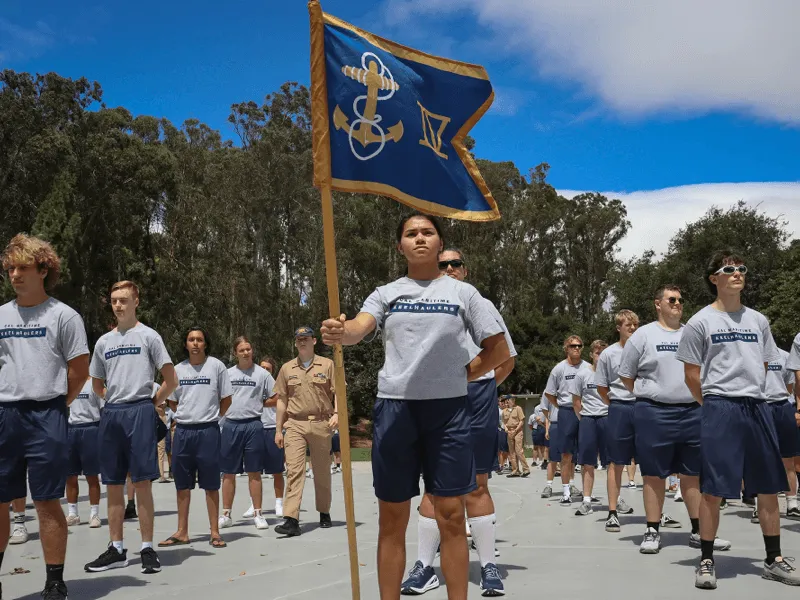 Cadetes de uniforme desfilando con una bandera