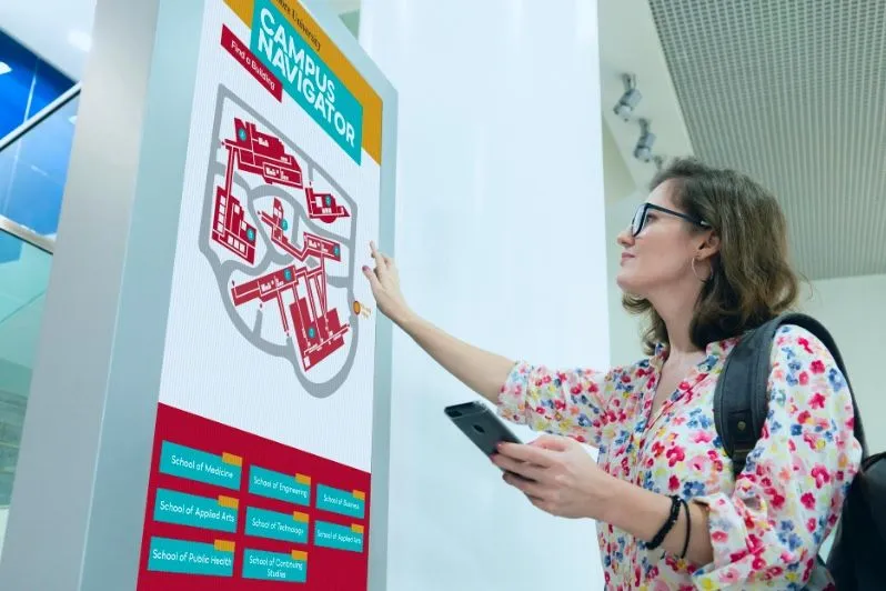Estudiante usando un plano interactivo del campus en una pantalla táctil