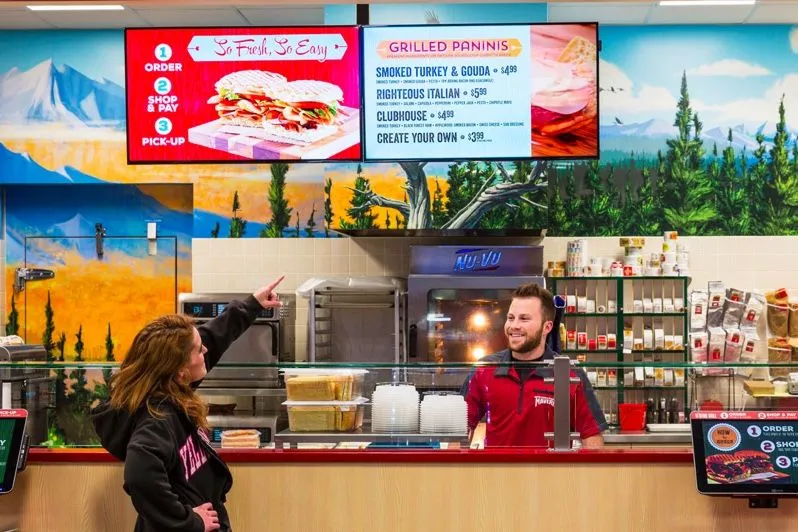 Mostrador de una tienda de la gasolinera con menús digitales encima