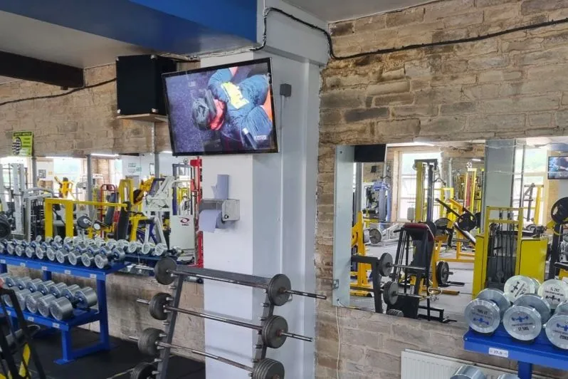 Pantalla con un vídeo de entrenamiento sobre una zona de pesas