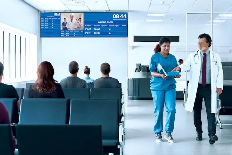 Sala de espera de un hospital con pantallas sobre los asientos