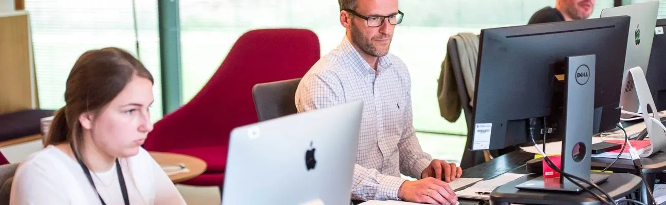 Personas trabajando en escritorios en una oficina diáfana