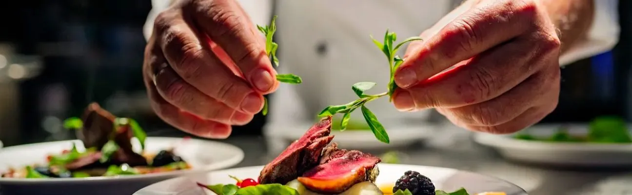 Cocinero emplatando un plato en la cocina de un restaurante