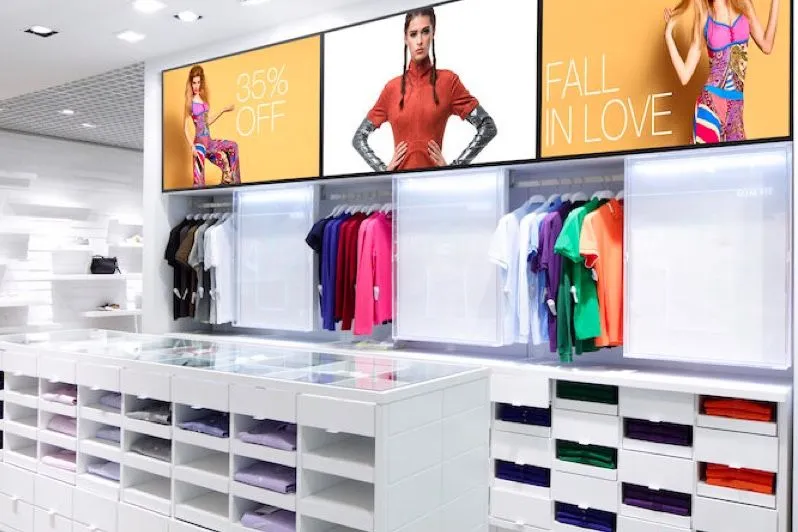 Tienda de moda con pantallas digitales sobre los percheros