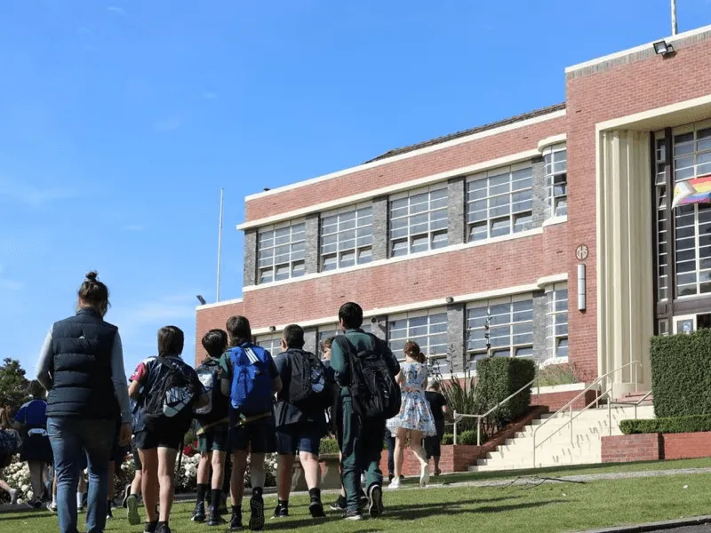 Alumnos caminando hacia un edificio escolar