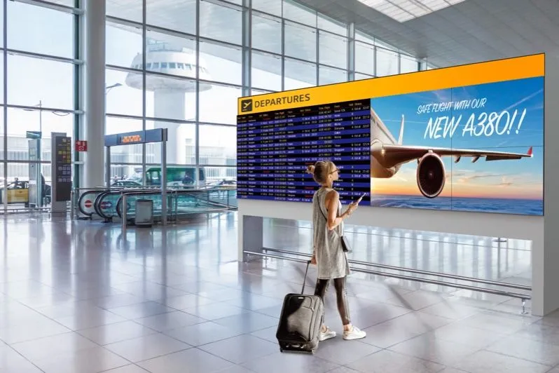 Viajero con una maleta frente a un panel de salidas en un aeropuerto